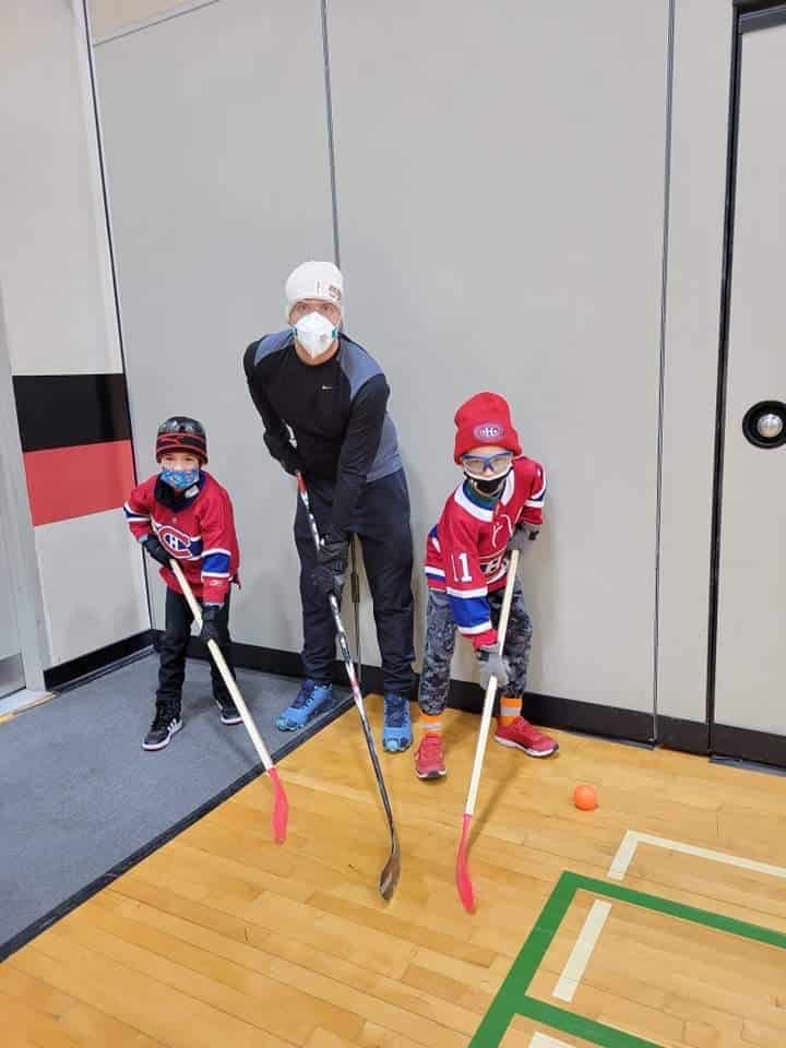 Enseignant et deux élèves jouent au hockey